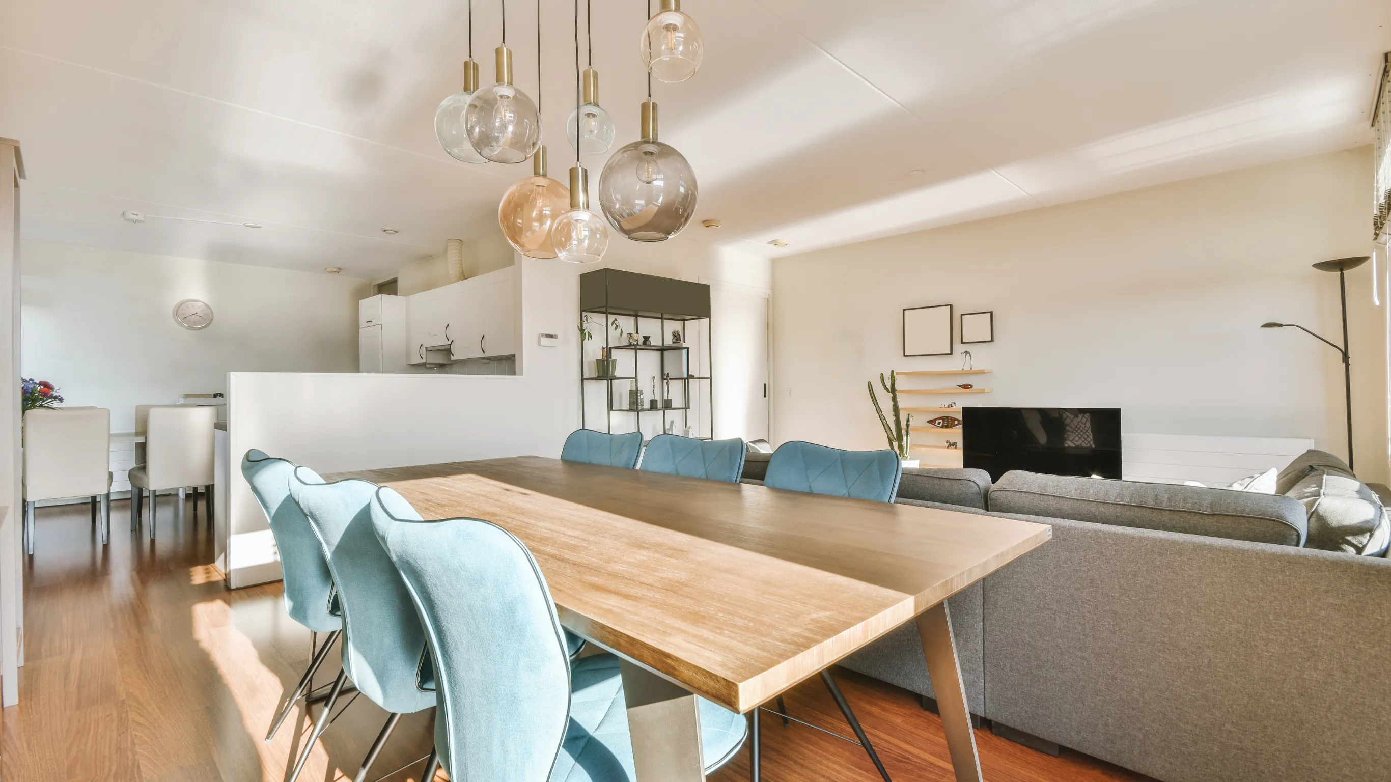 After residential remodeling project in Los Angeles showing an open-concept dining and living room with updated wood flooring, modern pendant lighting, bright walls, kitchen connection, and refreshed interior finishes