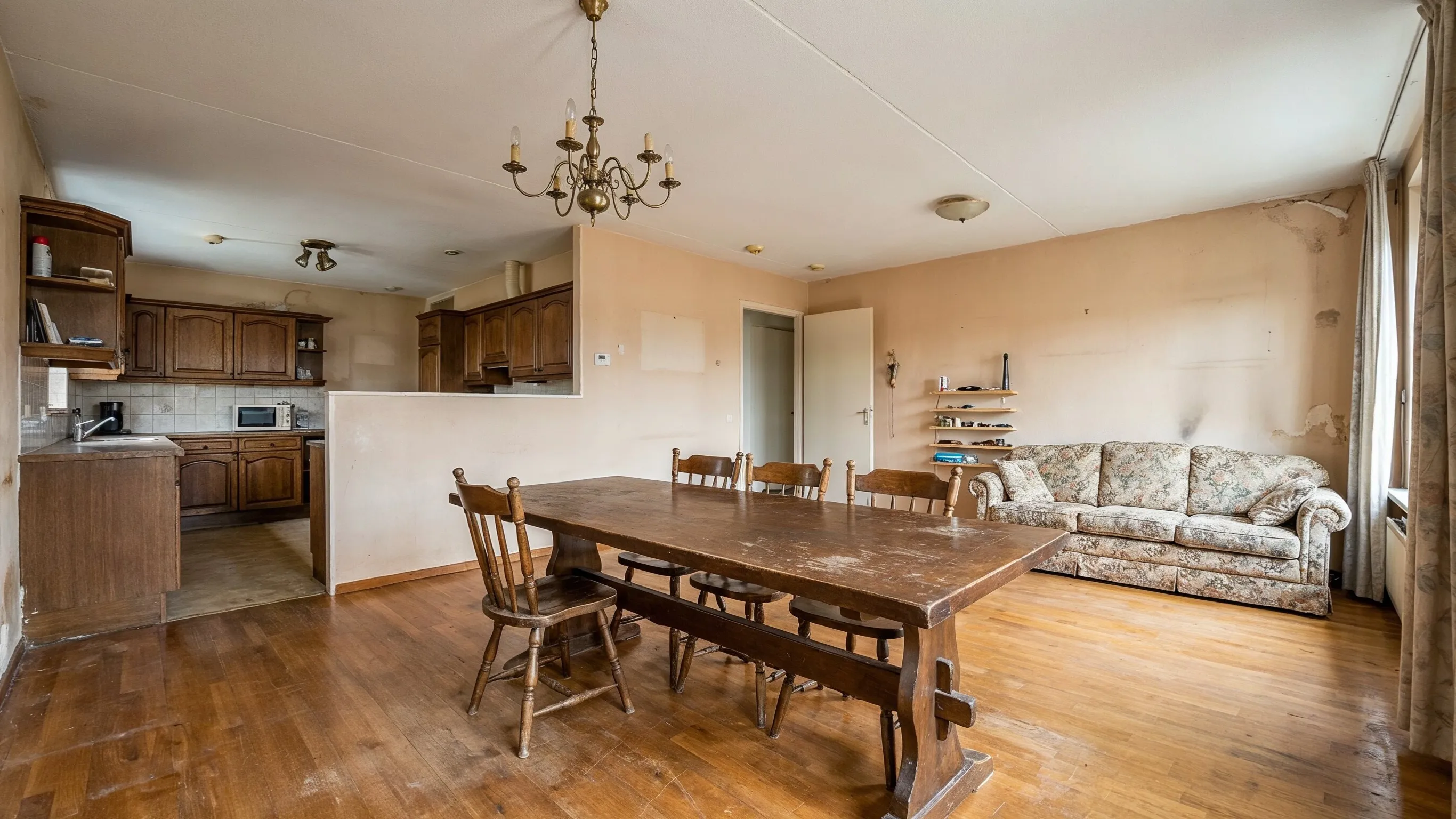 Before residential remodeling project in Los Angeles showing an outdated living and dining room with older wood cabinets, worn furniture, dated lighting, hardwood floors, and aging interior finishes