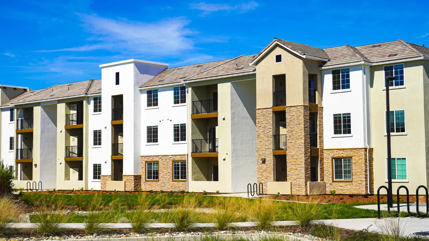 HOA remodeling project in Los Angeles showing a multifamily apartment building exterior with balconies, stucco walls, stone accents, landscaped common area, sidewalks, and upgraded community property design