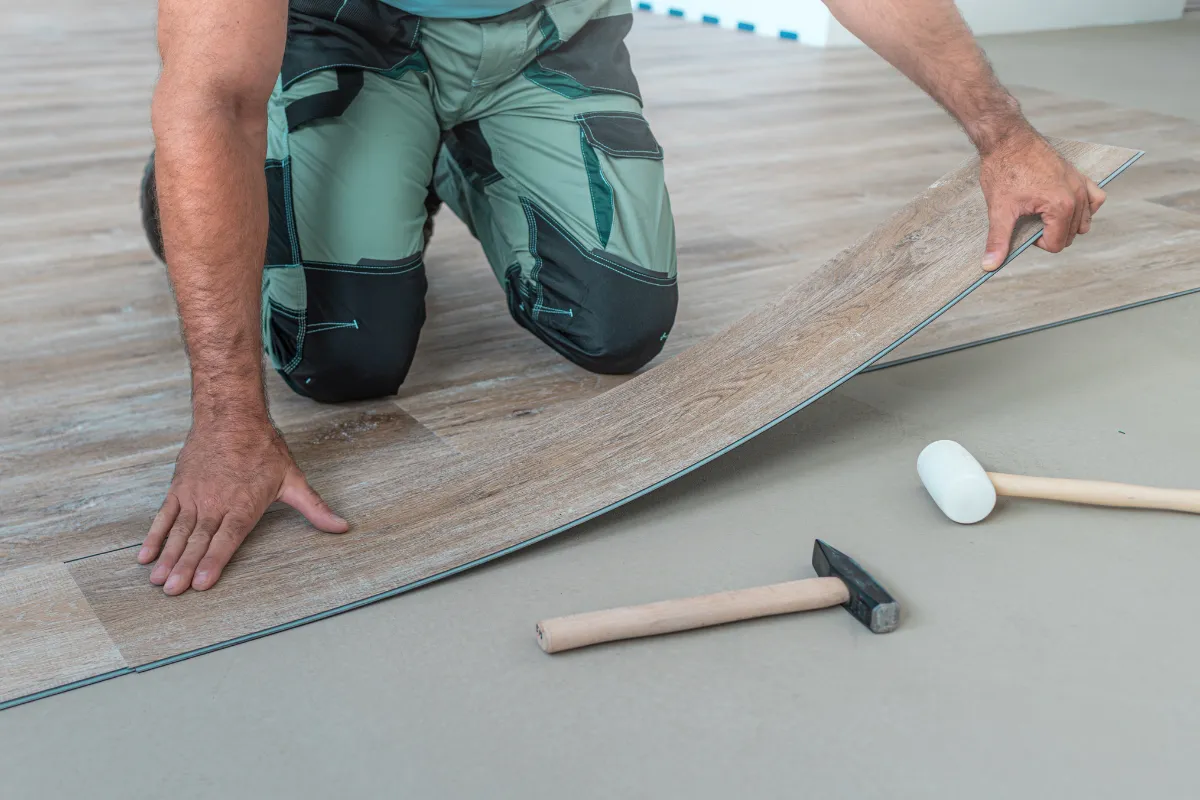 Flooring installation in Los Angeles with a worker installing luxury vinyl plank flooring using professional tools