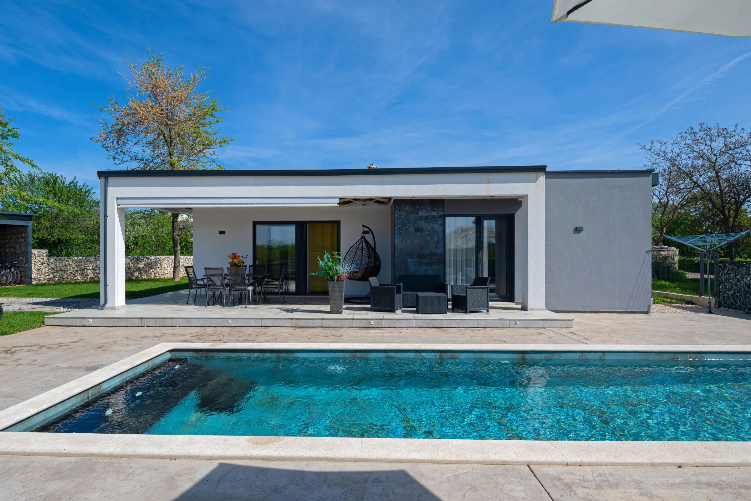 ADU construction in Los Angeles showing a modern detached backyard unit with patio seating, sliding glass doors, pool area, and clean exterior design