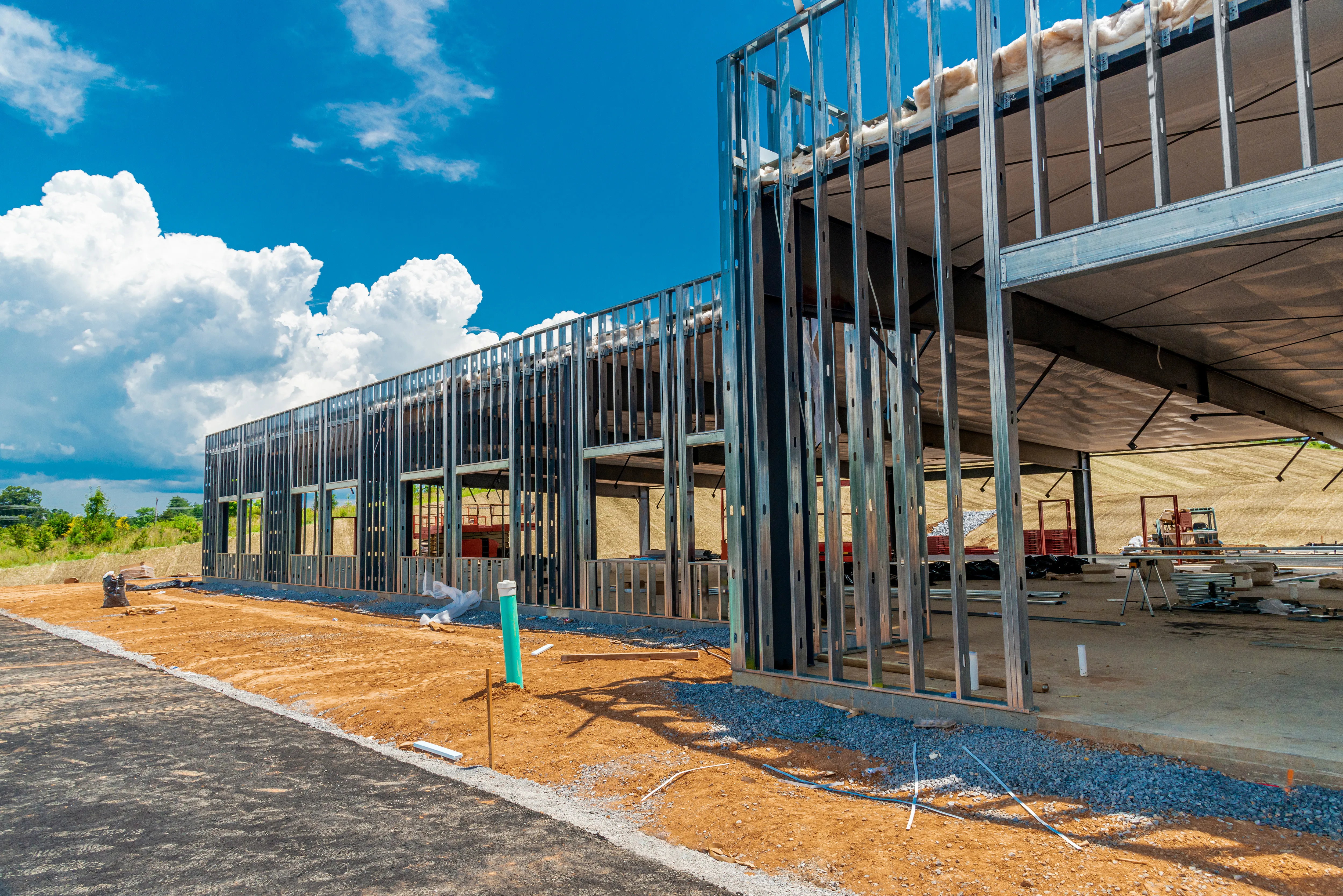 Commercial building construction in Los Angeles showing metal wall framing, structural steel studs, insulation, concrete slab, and active jobsite preparation