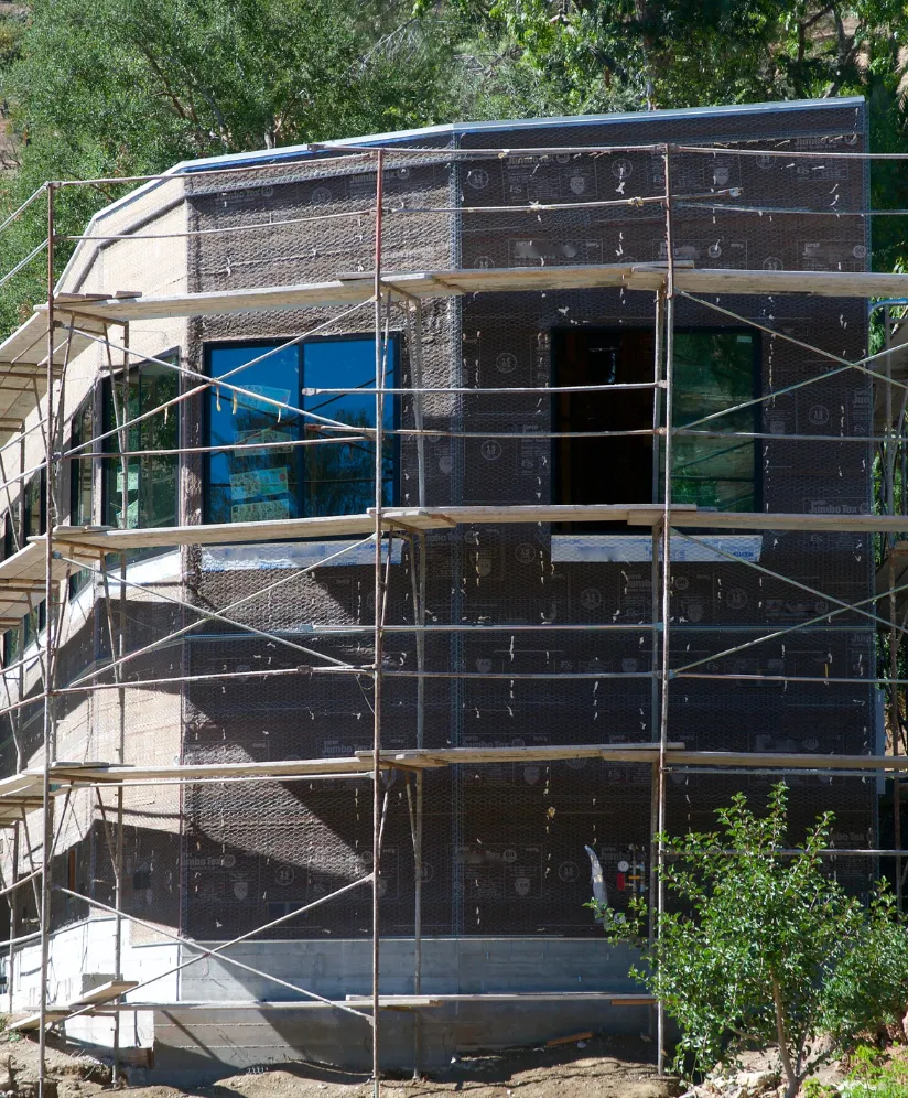 Los Angeles commercial remodeling project showing exterior facade renovation with scaffolding, building wrap, large windows, and exterior construction work