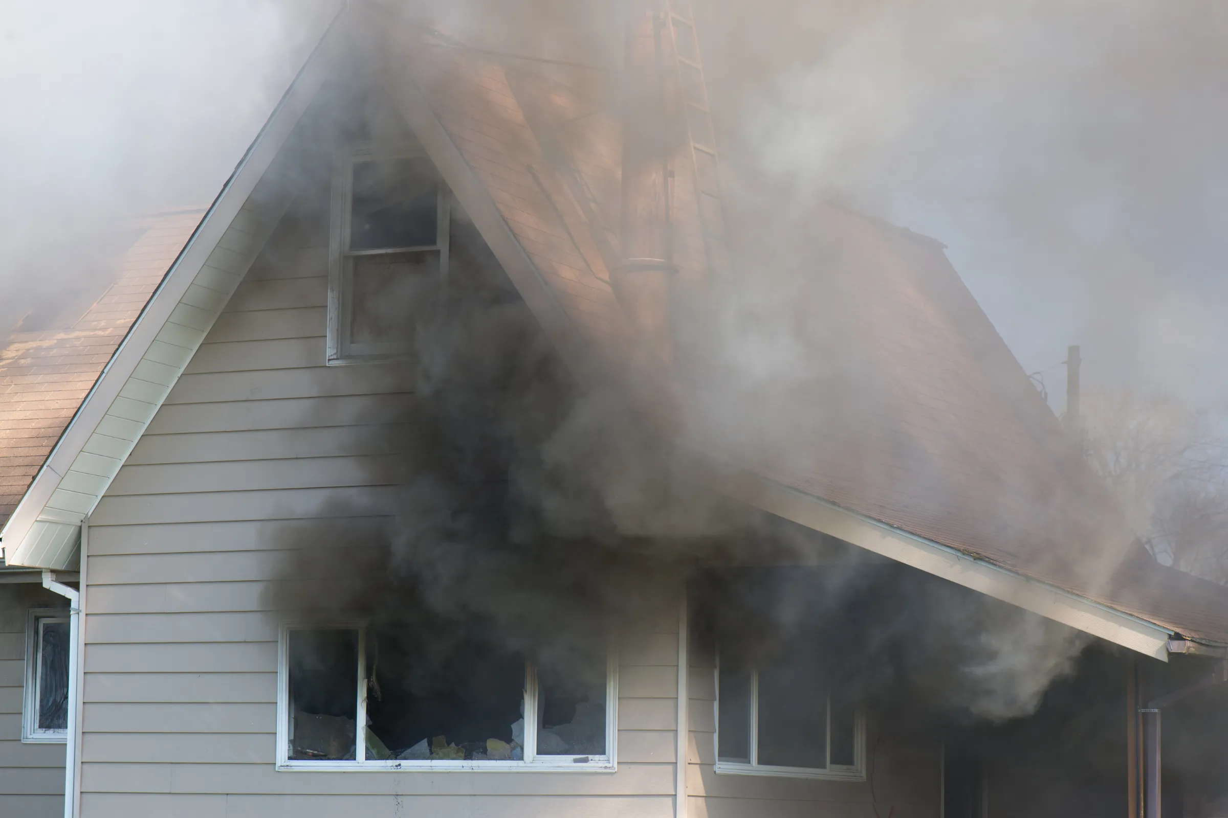 Home restoration in Los Angeles showing a house with heavy smoke damage, broken windows, roof damage, and fire restoration work needed